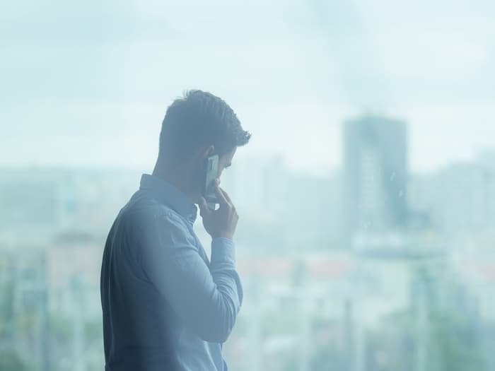 Mann steht am Fenster und telefoniert