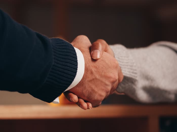 Handschlag zweier Personen über einem Tisch