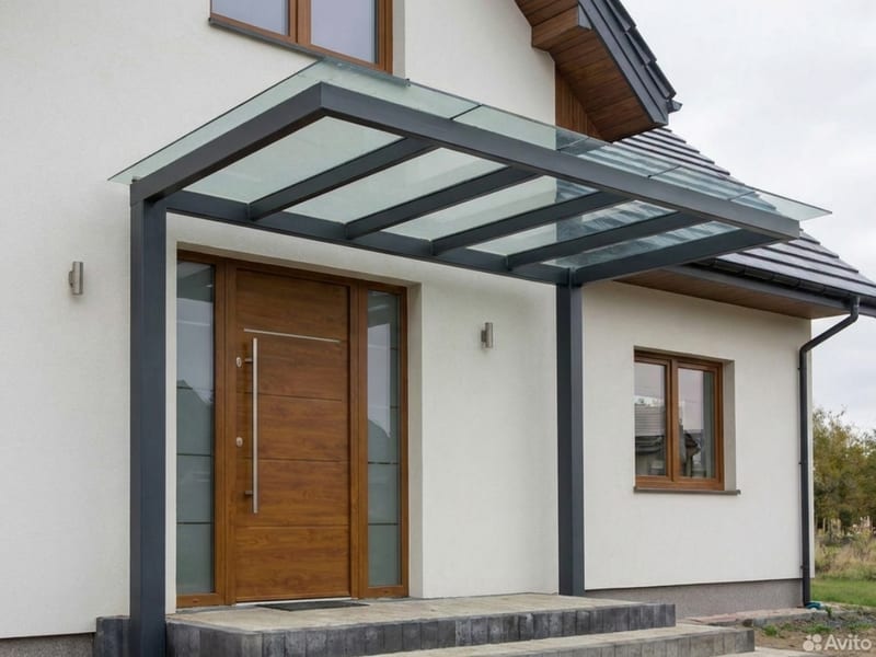 Vordach aus Glas mit anthrazitfarbenem Stahlrahmen über einer Haustür