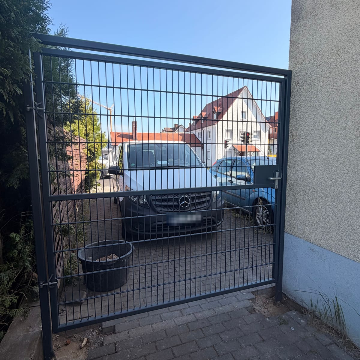 Anthrazitfarbenes Hoftor aus Doppelstabmatten mit Schloss, eingebaut in der Durchfahrt zwischen Hauswand und Hecke